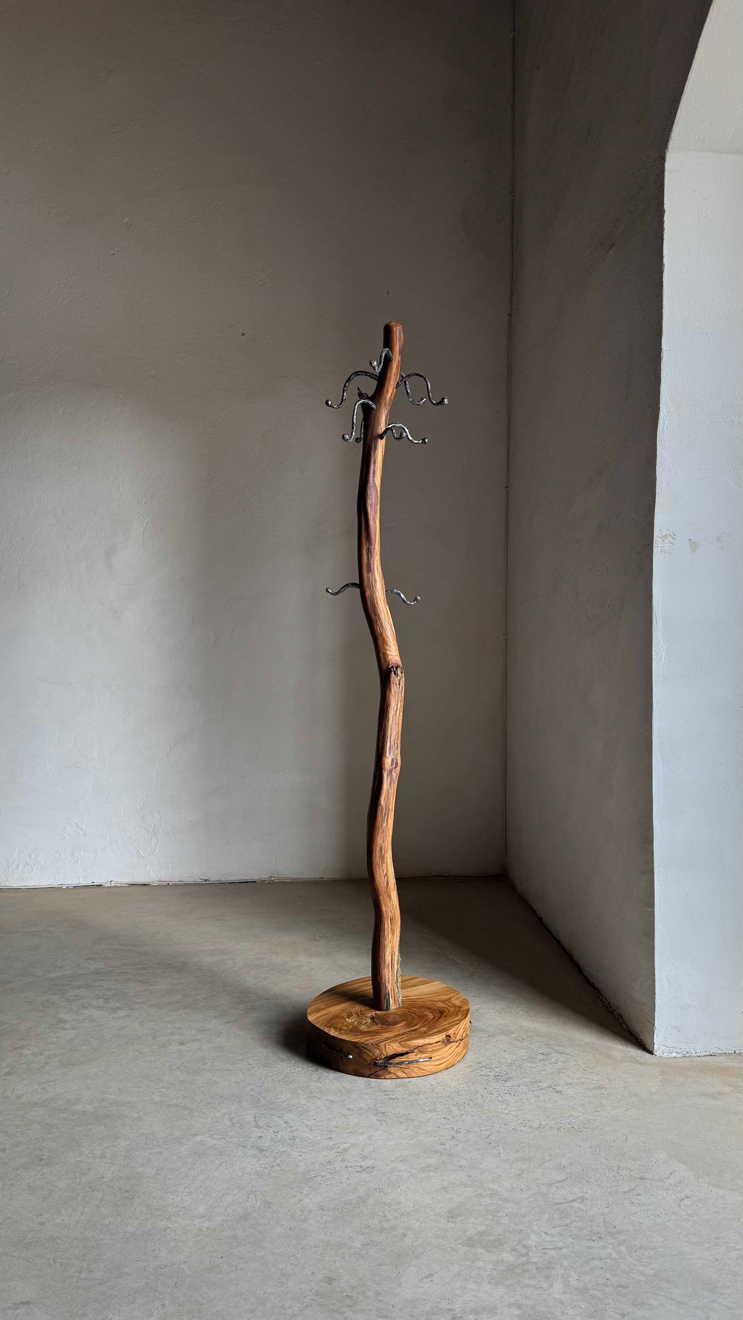 Oak Coat Rack with steel hangers Wooden coat stand against a plain wall.