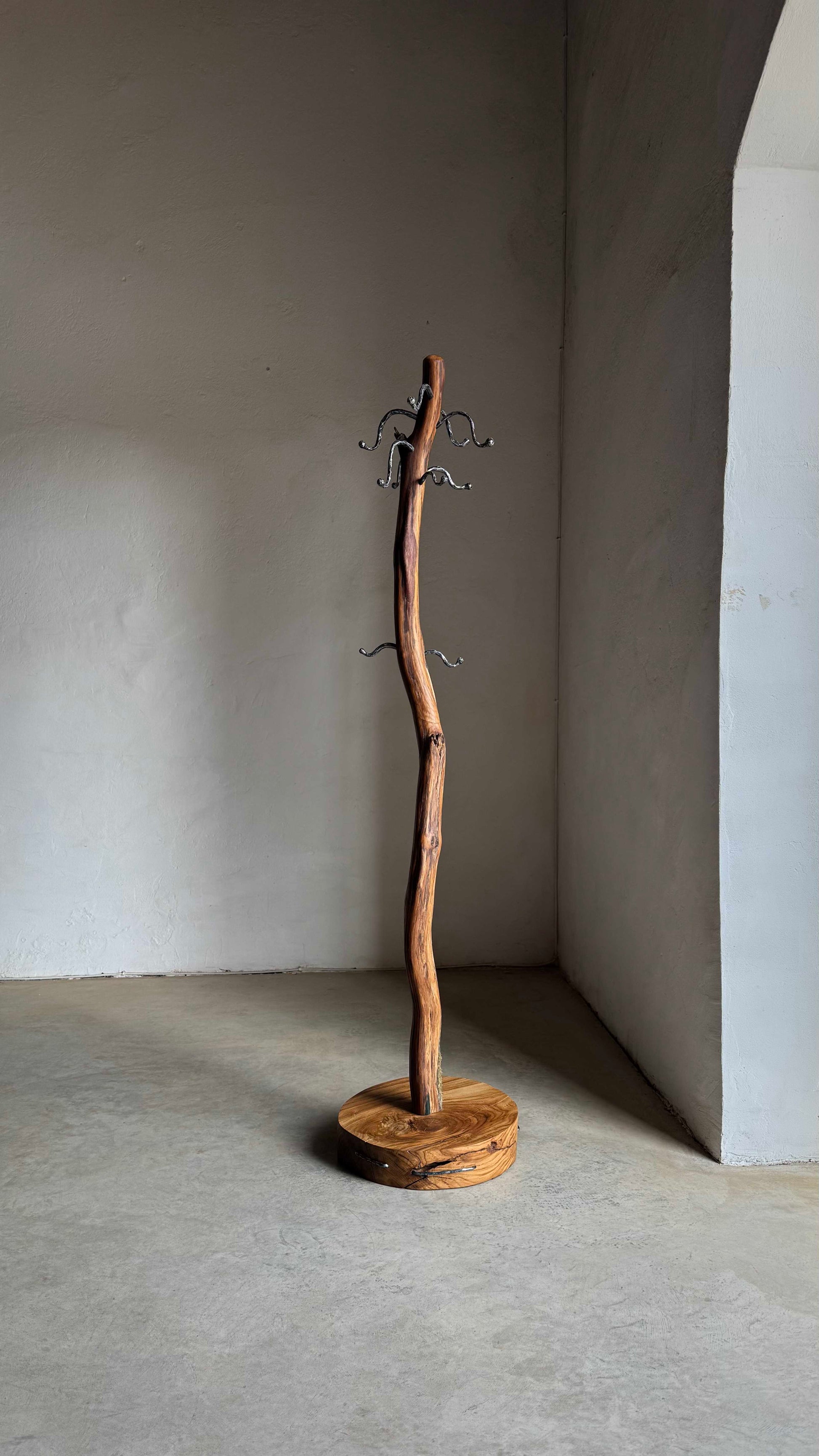 Oak Coat Rack with steel hangers Wooden coat stand against a plain wall.