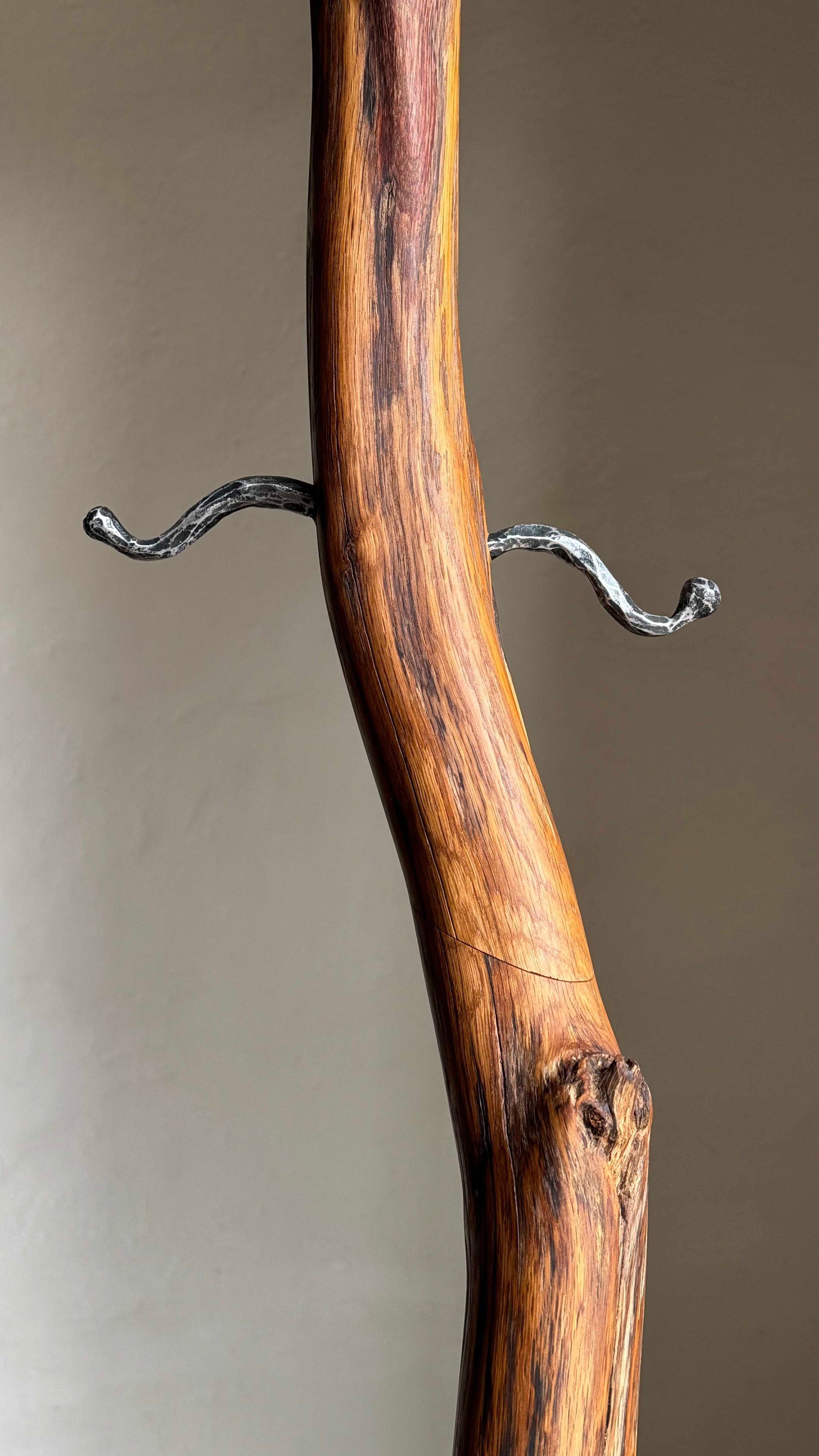 Oak Coat Rack with steel hangers Wooden coat stand against a plain wall.